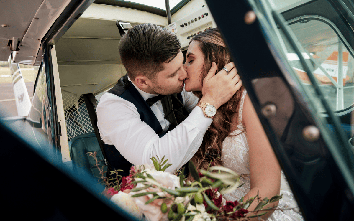 1 bride and groom kissing in plane