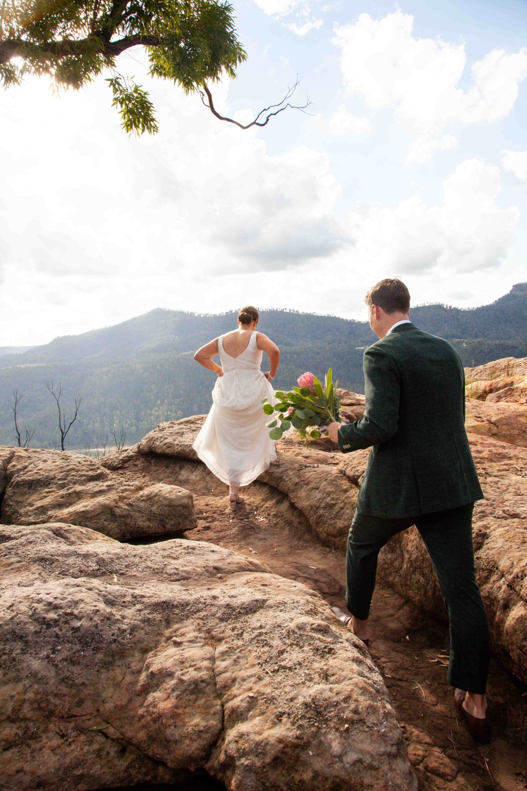 bride and groom climbing rocks at Kangaroo Valley Bush Retreat